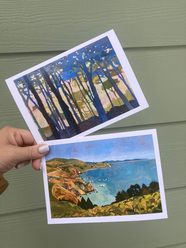 Two scenic postcards held by a hand against a green background