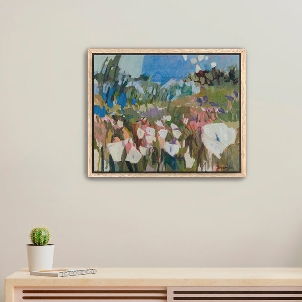 Framed painting of a landscape with people on a wall above a wooden console table.