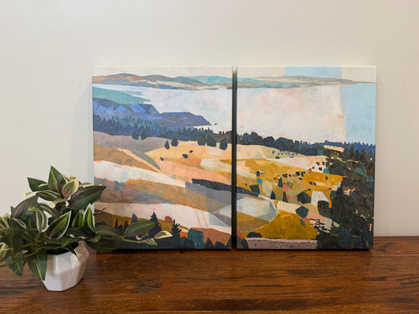 Two-panel landscape painting on a wooden surface with a plant.