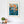 Framed abstract art piece on a white wall with decor items below.