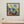 Framed abstract painting on a wall above a wooden console table with a cactus plant.