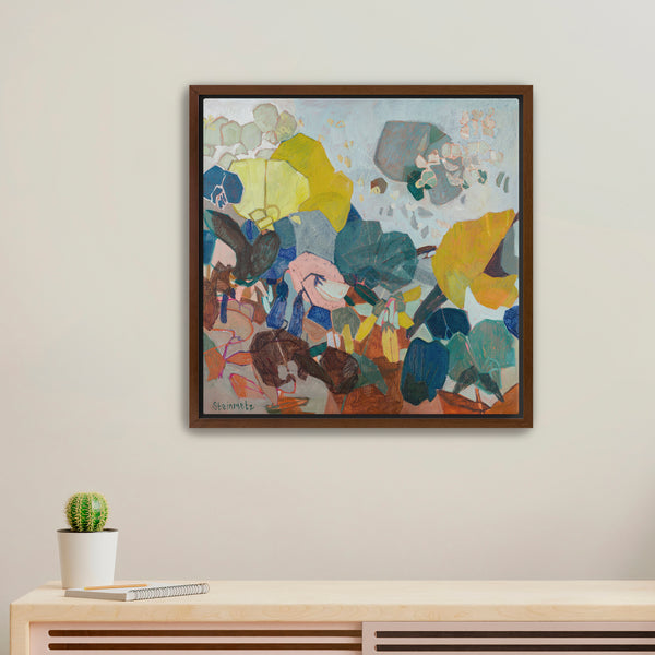 Framed abstract painting on a wall above a wooden console table with a cactus plant.