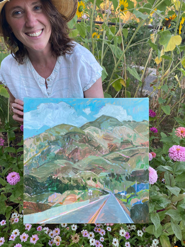 Lady with painting sitting outside in flowers