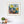 Framed abstract artwork on a white wall with a desk and decor items below.