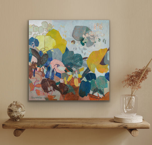Abstract painting on a wall above a wooden shelf with decorative items.