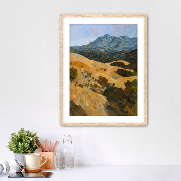 Framed landscape painting on a wall with decor items below